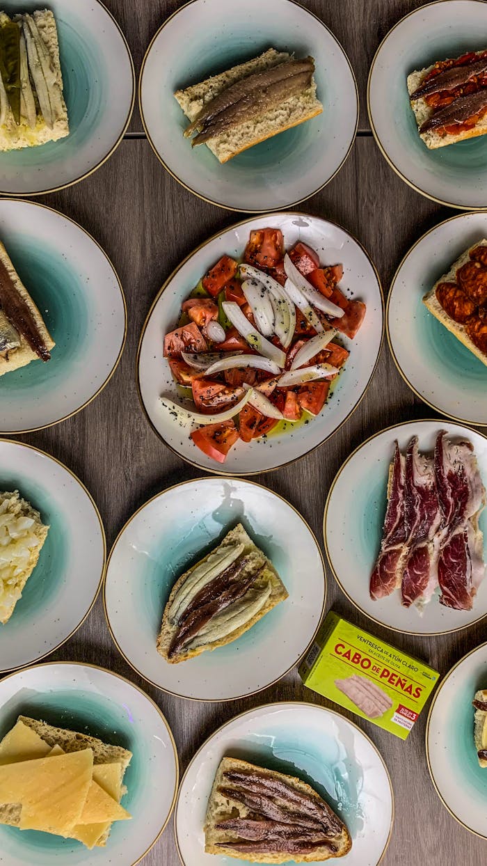 Aerial view of eclectic Spanish tapas spread on elegant ceramic plates.