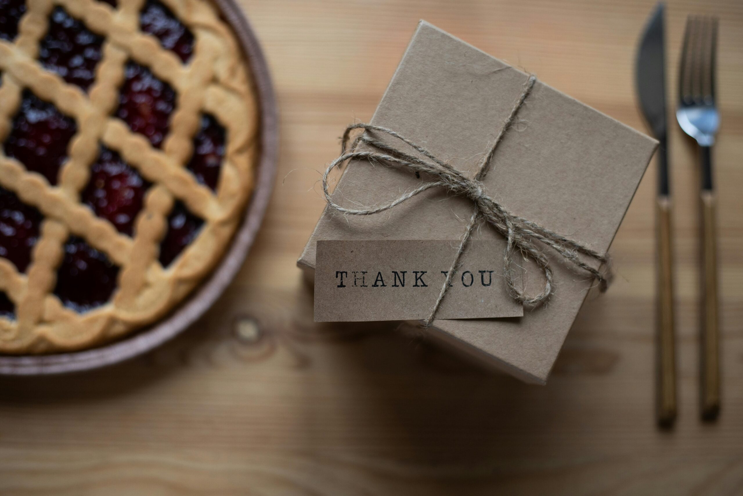 A rustic thank you gift box beside a cherry pie, perfect for celebrations.